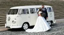 Newly married couple beside cream 1972 Volkswagen Split Screen campervan outside Liverpool Registry Office.