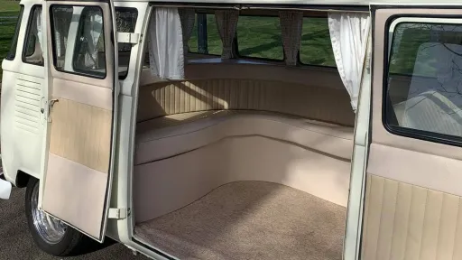 Rear interior of cream 1972 Volkswagen Split Screen campervan showing spacious L shaped seating and luggage area.