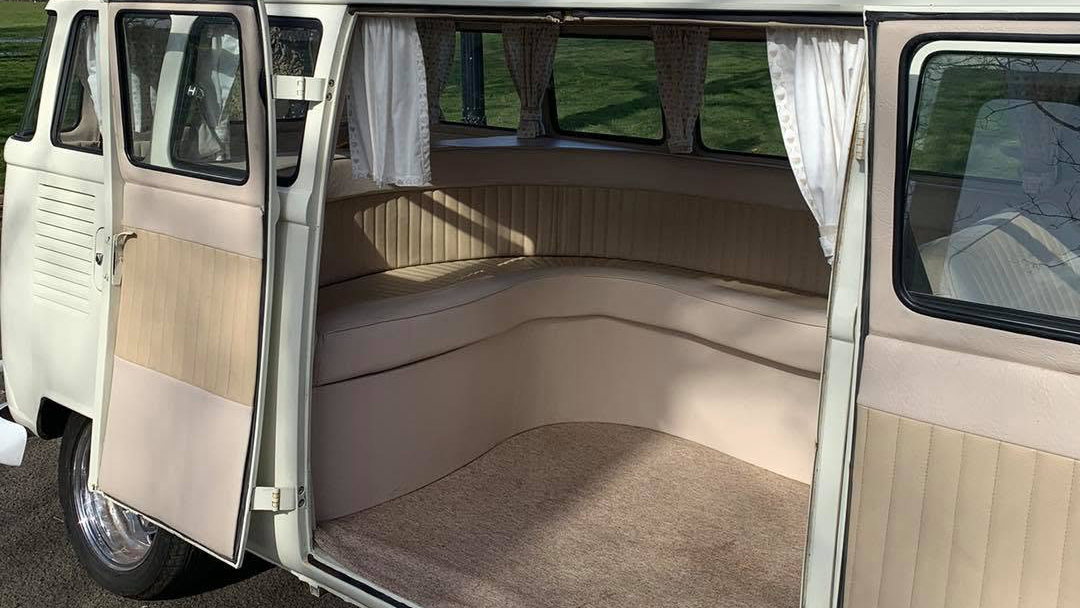 Rear interior of cream 1972 Volkswagen Split Screen campervan showing spacious L shaped seating and luggage area.