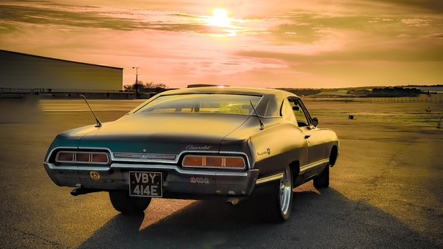 Rear view of black 1967 Chevrolet Impala Fastback photographed at sunset.