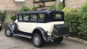 Rear three quarter view of navy blue and ivory Bramwith limousine showing luggage trunk and classic styling.