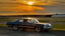 Right side profile of black 1967 Chevrolet Impala Fastback parked at sunset.