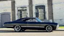 Right side view of black 1967 Chevrolet Impala Fastback parked outside industrial heritage building.