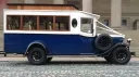 Right side view of navy blue and Old English White Asquith vintage wedding bus with large mahogany windows.