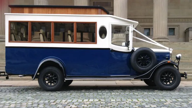 Right side view of navy blue and Old English White Asquith vintage wedding bus with large mahogany windows.