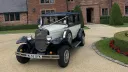 Navy blue and ivory Badsworth Landaulette parked outside country house with chrome headlamps and wire wheels.
