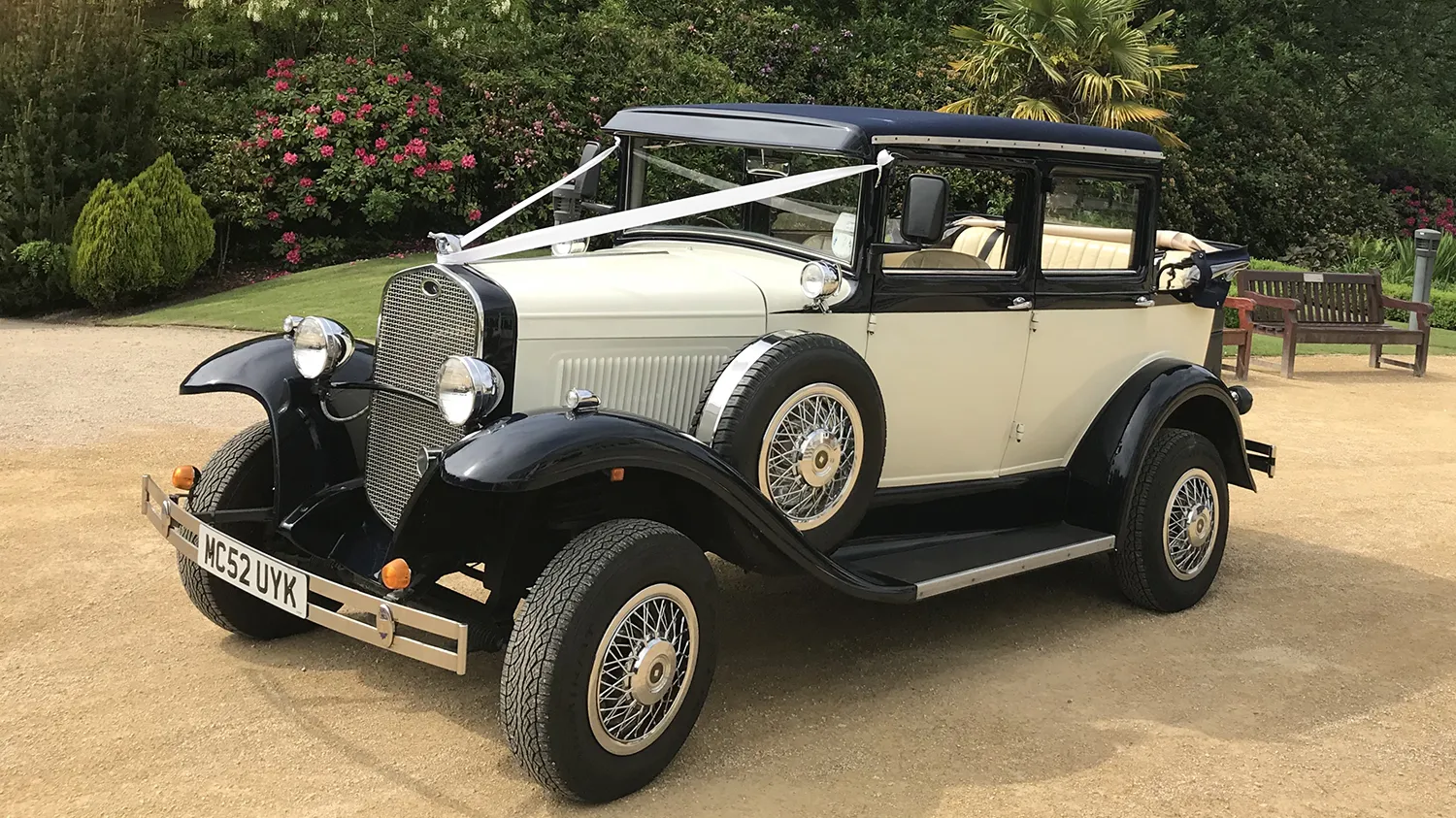 Front three quarter view of navy blue and ivory Badsworth Landaulette with folding rear roof, chrome radiator and side mounted spare wheel.
