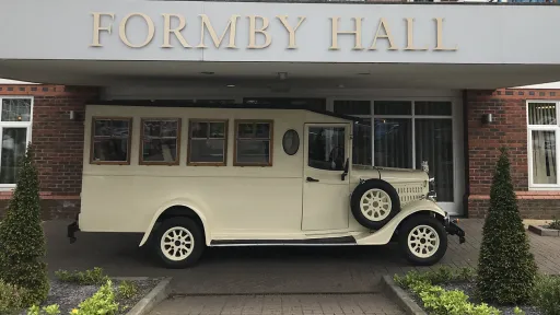 Side view of Old English White Asquith vintage wedding bus parked outside Formby Hall Hotel.