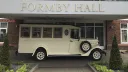 Side view of Old English White Asquith vintage wedding bus parked outside Formby Hall Hotel.