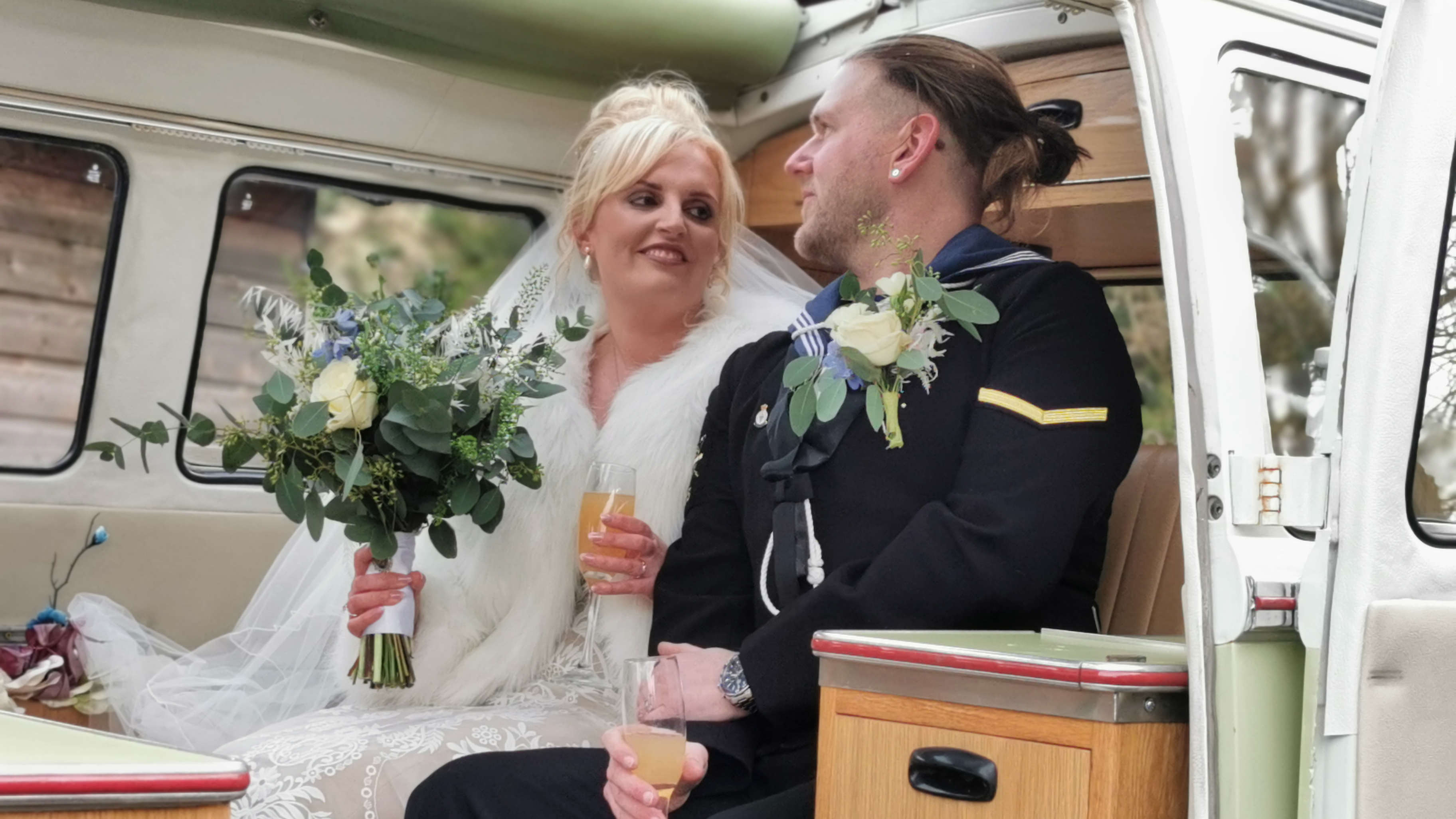 Bride and groom seated inside cream and green Volkswagen Split Screen campervan with vintage interior.