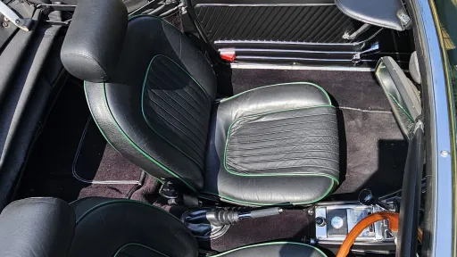 Aerial view of black leather seats and classic interior inside green Alfa Romeo Spider Veloce convertible.