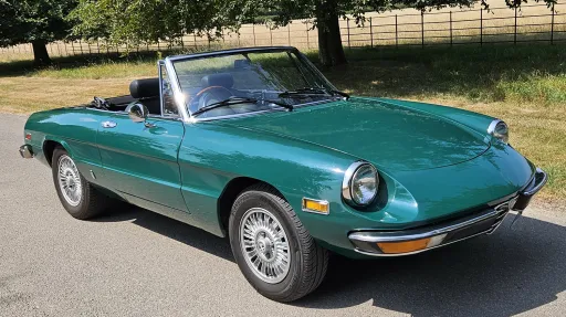 Front three quarter view of dark racing green Alfa Romeo Spider Veloce convertible with roof down.