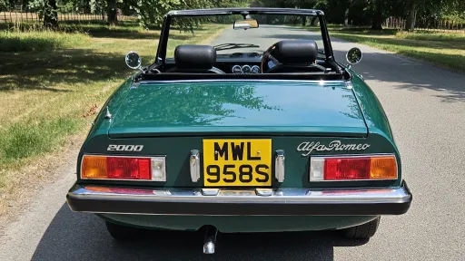 Rear view of dark racing green Alfa Romeo Spider Veloce with black soft top folded down.