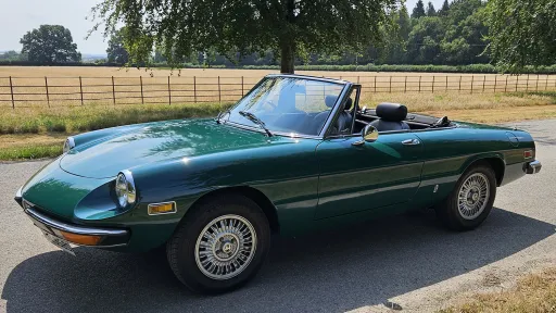 Left side view of dark racing green Alfa Romeo Spider Veloce convertible with roof folded down.