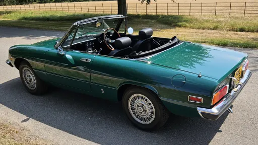 Rear three quarter view of dark racing green Alfa Romeo Spider Veloce convertible with roof open.