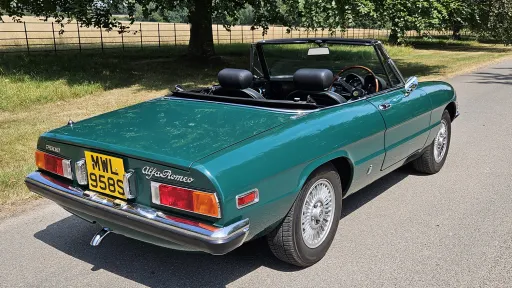 Rear right view of dark racing green Alfa Romeo Spider Veloce with black leather interior visible.