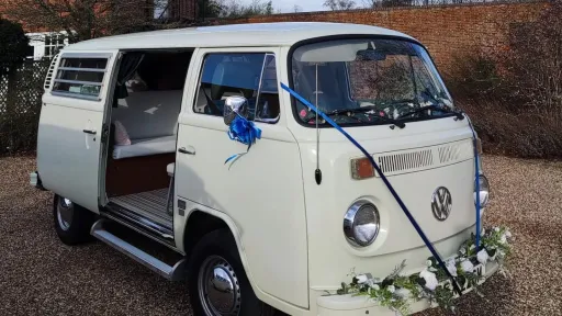Front view of white 1974 Volkswagen Bay Window campervan decorated with blue wedding ribbons and flowers.