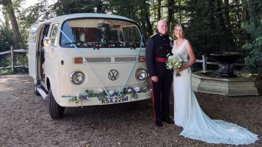 Bride and groom standing beside white 1974 VW Bay Window campervan at an Essex wedding venue.