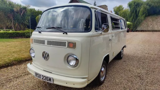 Front three quarter view of white 1974 Volkswagen Bay Window campervan parked on a country driveway in Essex.