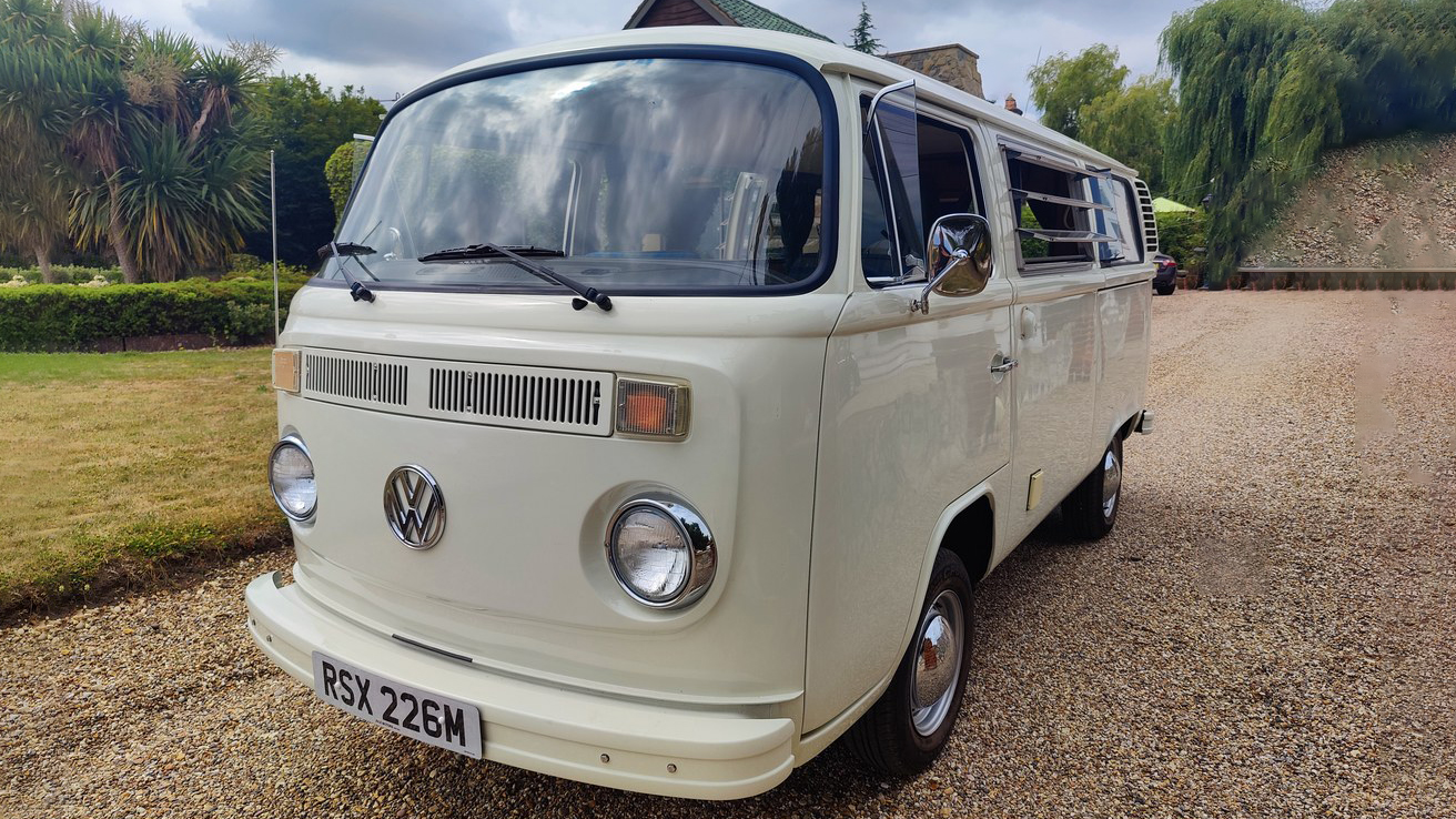 Front three quarter view of white 1974 Volkswagen Bay Window campervan parked on a country driveway in Essex.