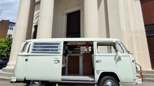 Right side view of white 1974 VW Bay Window campervan with sliding passenger door open showing the interior.