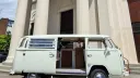 Right side view of white 1974 VW Bay Window campervan with sliding passenger door open showing the interior.