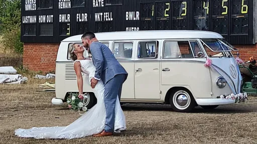 Bride and groom kissing beside cream and beige 1964 VW Split Screen Campervan decorated for a wedding.