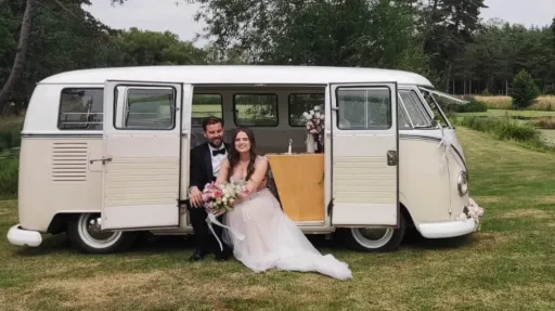 Bride and groom seated inside cream and beige 1964 VW Split Screen Campervan in the Essex countryside.