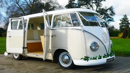 Side view of cream and beige 1964 VW Split Screen Campervan decorated with blue wedding ribbons.
