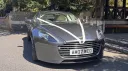 Front view of metallic silver Aston Martin Rapide S showing its distinctive grille, bonnet and four door body.