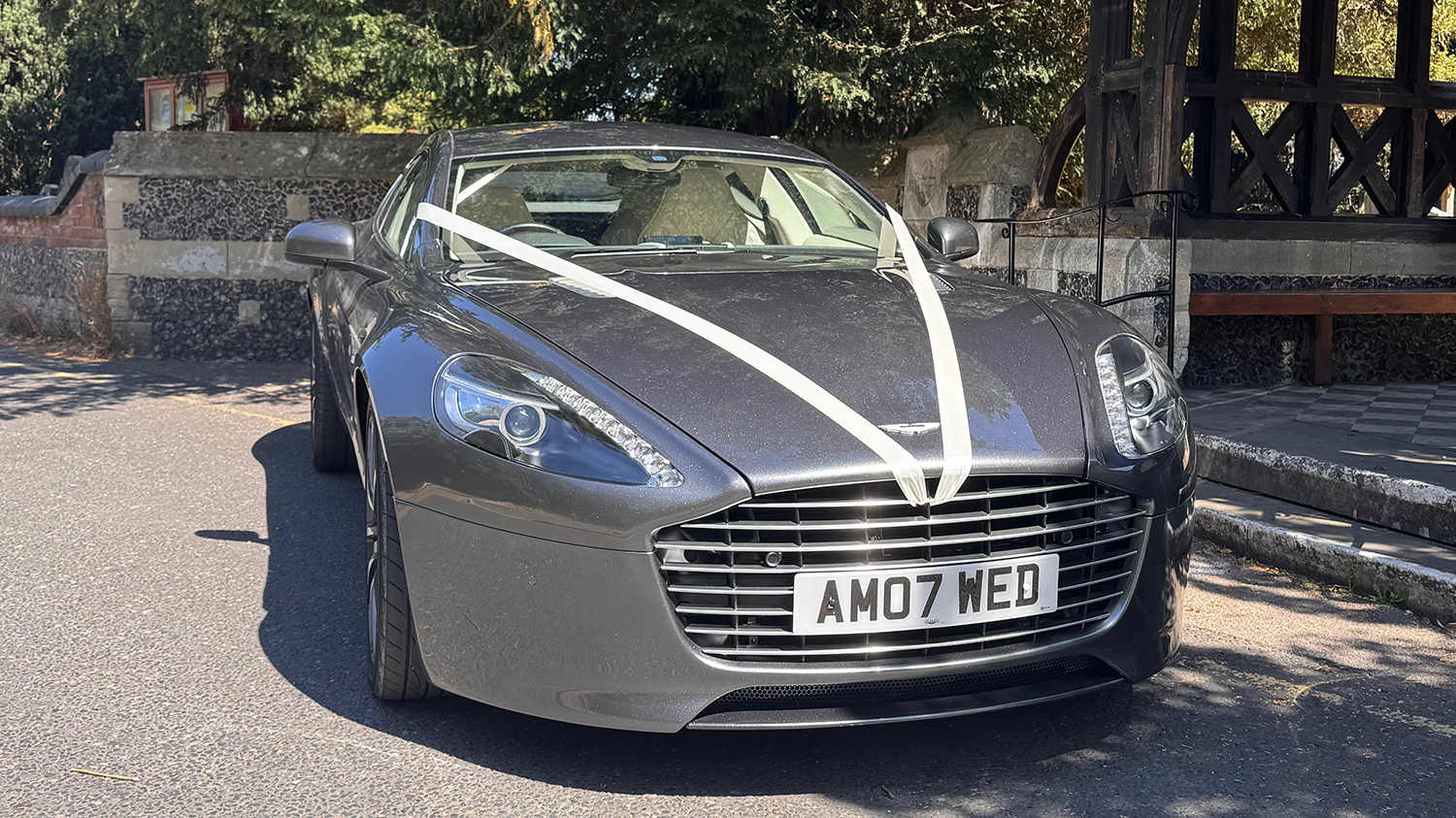 Front view of metallic silver Aston Martin Rapide S showing its distinctive grille, bonnet and four door body.