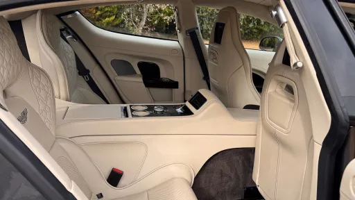 Rear passenger area of Aston Martin Rapide S showing individual quilted cream leather seating and centre console.