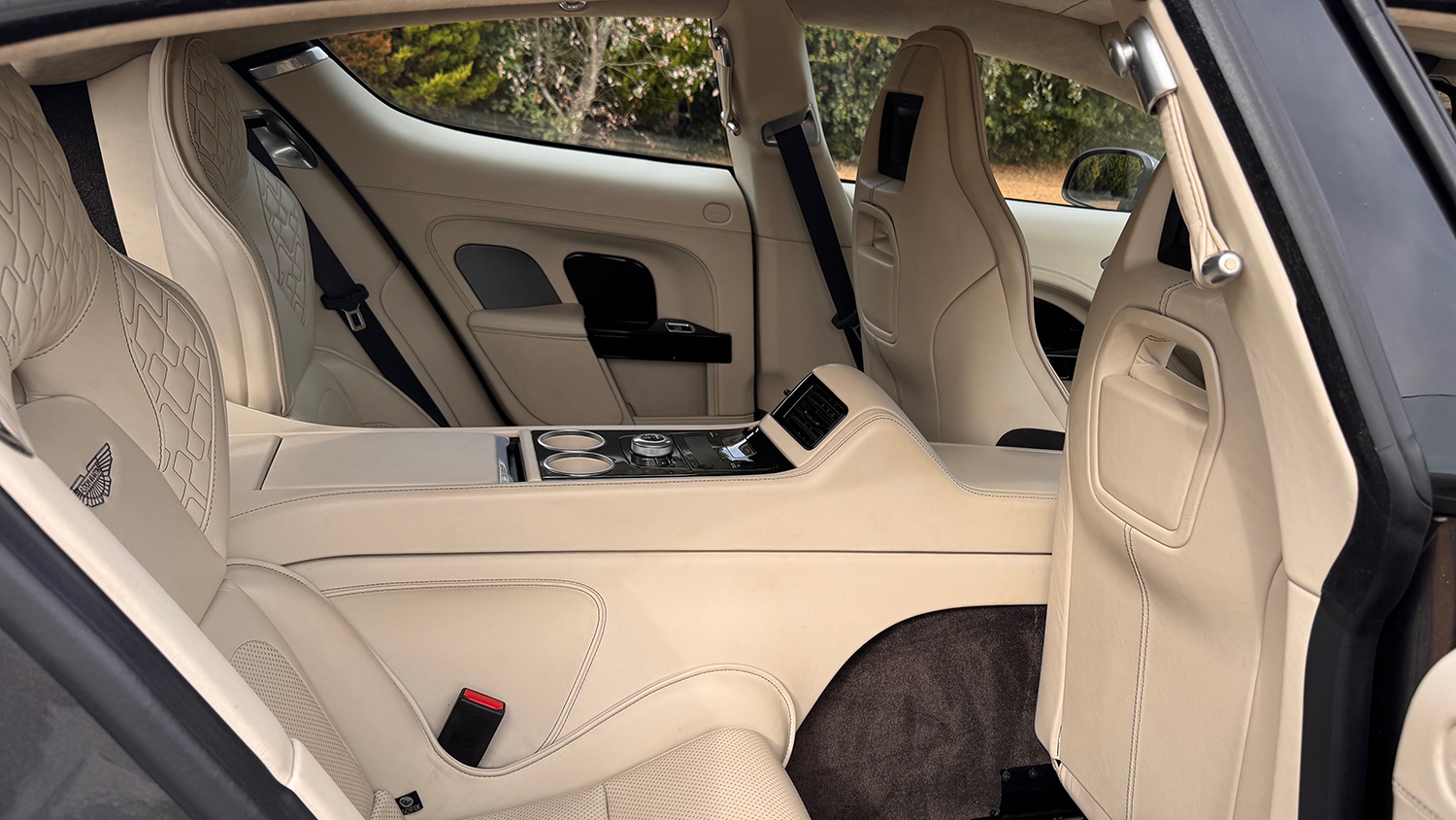 Rear passenger area of Aston Martin Rapide S showing individual quilted cream leather seating and centre console.