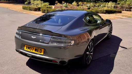 Rear three quarter view of metallic silver Aston Martin Rapide S showing its sweeping roofline and rear styling.