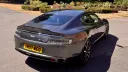 Rear three quarter view of metallic silver Aston Martin Rapide S showing its sweeping roofline and rear styling.