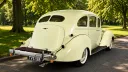 Rear three quarter view of cream 1937 Hudson Terraplane showing its sweeping bodywork, chrome bumper and whitewall tyres.