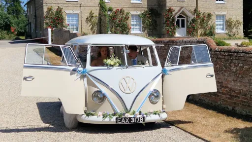 Bride and Groom seating in the front passenger seats of a Splitscreen campervan with Safari windows open