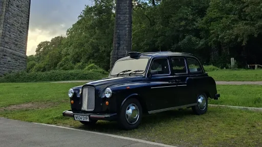 Classic black taxi cab parked beneath the stone Porthkerry Viaduct near Barry in South Wales.