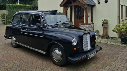 Classic black taxi cab parked outside a house ready for wedding transport in South Wales.