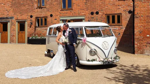 Bride and Groom kissing in front of a cream and White classic campervan