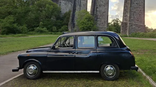 Left side view of classic black taxi cab parked beside Porthkerry Viaduct near Barry, South Wales.