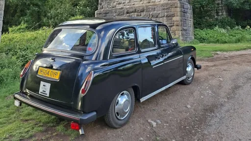 Rear three quarter view of classic black taxi cab parked in a countryside setting near Barry, South Wales.