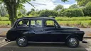 Right side profile of classic black taxi cab showing its traditional London taxi bodywork and chrome hubcaps.
