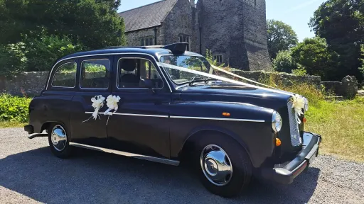 Classic black taxi cab with wedding ribbons parked outside a church in Barry, South Wales.