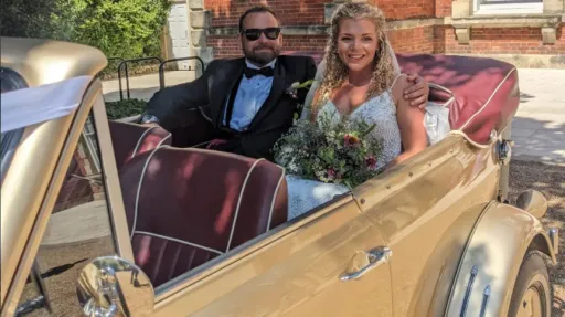 Bride and groom seated inside gold Beauford Convertible showing the burgundy leather interior and open-top cabin.
