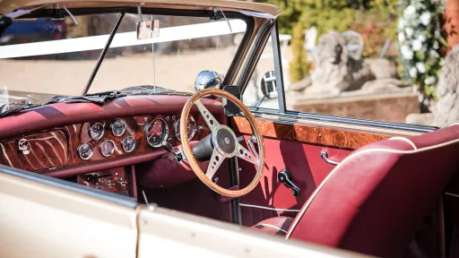Interior view of gold Beauford showing burgundy dashboard, classic instruments, wooden steering wheel and Maroon Red seating.