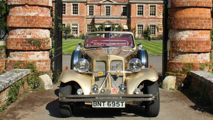 Front view of gold Beauford Convertible showing chrome grille, large headlamps and traditional vintage-style bodywork.