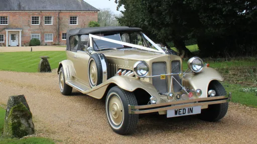 Front three-quarter view of gold Beauford Convertible wedding car parked in the Wiltshire countryside.