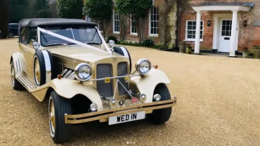 Gold Beauford Convertible decorated with ivory wedding ribbons and bows outside a country property.