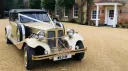 Gold Beauford Convertible decorated with ivory wedding ribbons and bows outside a country property.
